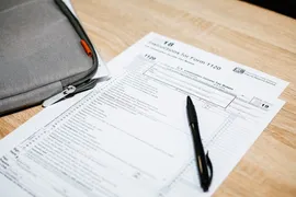 A printed IRS form on a table with a black pen on top.