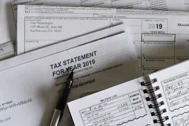 Tax documents scattered with a pen on top.