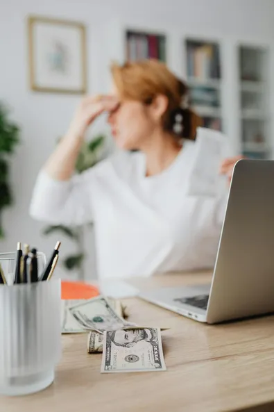 Stressed out woman holding a receipt with her hand on her forehead.